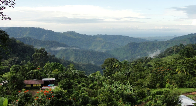 A vast landscape of green mountains lie under a blue sky